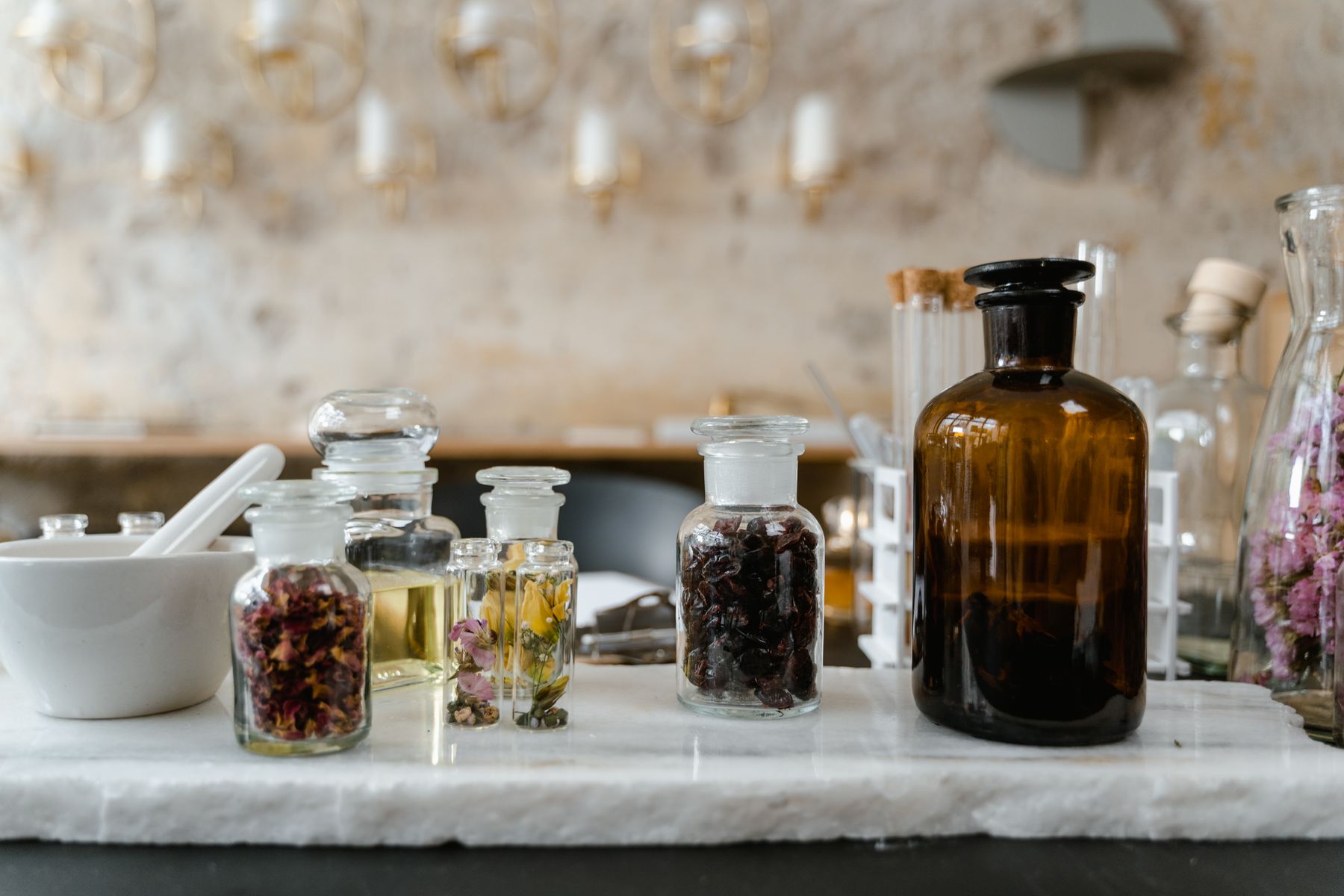 Aromatic oils and dried flowers displayed in clear glass bottles